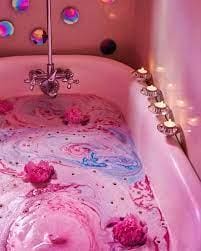 A pink bath tub with candles and flowers in it.